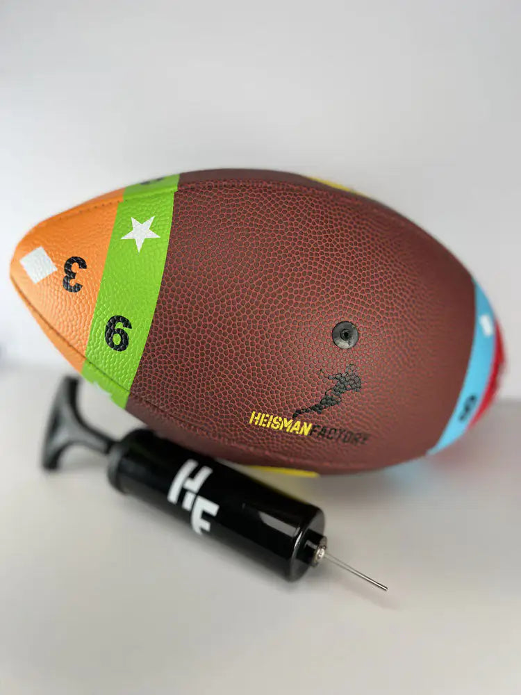 Colorful football with Heisman Trophy branding and a black pump on a white background