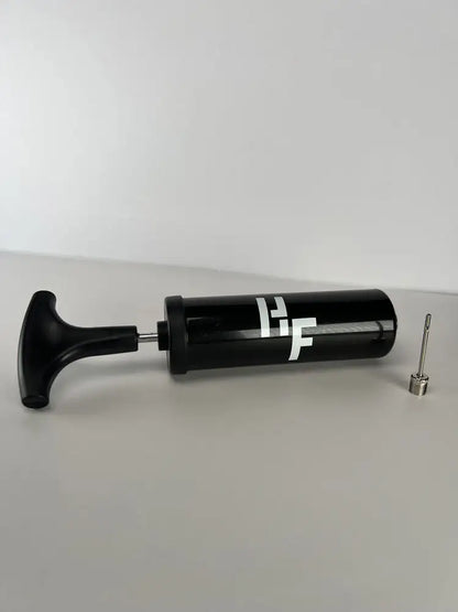 A black essential football pump with a needle attachment, placed against a light background.